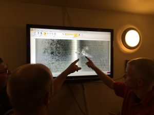 two people pointing at an image of a scan of a shipwreck