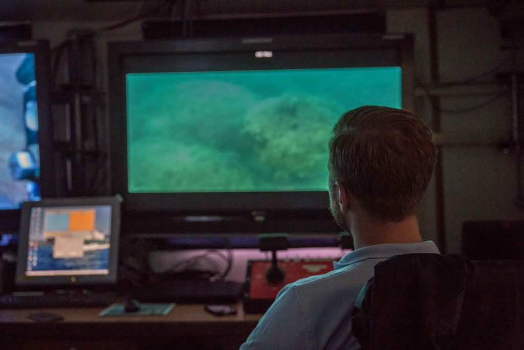 Mateusz Polakowski looking at a screen showing underwater camera footage