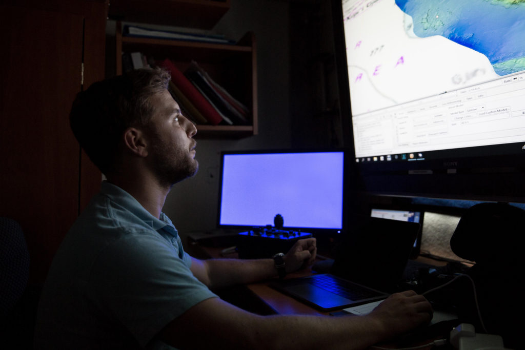 Mateusz Polakowski looking at a screen showing underwater site