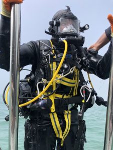 a diver in full SCUBA gear descending the ladder of a boat.