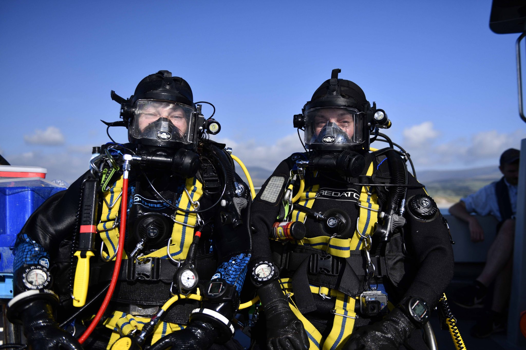 two divers in full SCUBA gear sat on the boat