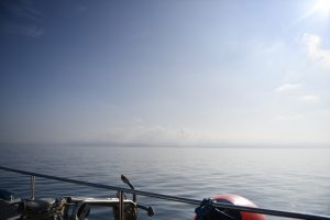 the view of the ocean from the side of a boat. it is calm and blue.